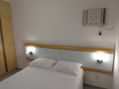 a bedroom with a white bed and a fan at Apart Hotel Quartier Latin in Vitória