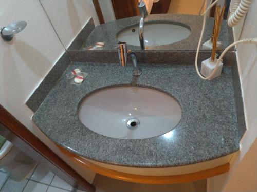 a bathroom counter with a sink with a faucet at Apart Hotel Quartier Latin in Vitória