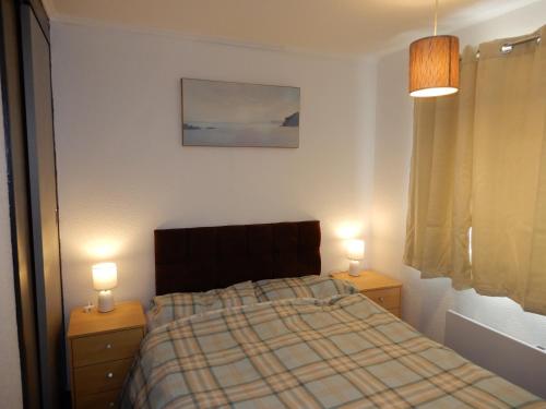 a bedroom with a bed and two night stands with lamps at 303 Sundowner in Hemsby