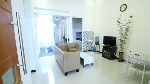 a living room with a chair and a television at Villa Harmoni Syariah by Masterpiece Villa in Karangploso