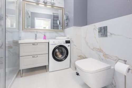 a bathroom with a washing machine and a toilet at Baltic Apartments Seaside Residence in Gdańsk