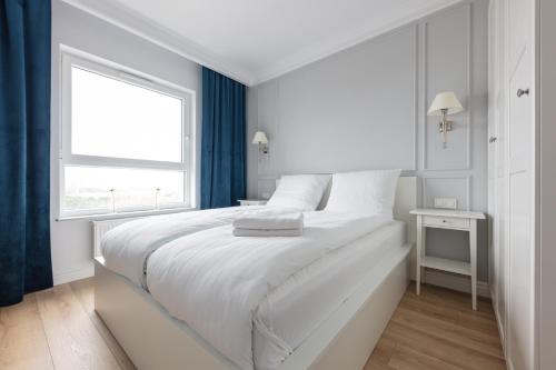 a white bedroom with a large bed and a window at Baltic Apartments Seaside Residence in Gdańsk