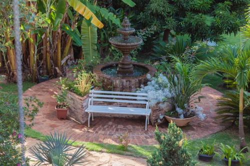 a bench in front of a fountain in a garden at Pousada Adega Cipo in Serra do Cipo