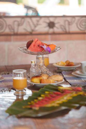 a table topped with a plate of food and orange juice at Pousada Adega Cipo in Serra do Cipo