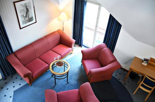 ein Wohnzimmer mit zwei roten Stühlen und einem Tisch in der Unterkunft Žalias namas in Palanga