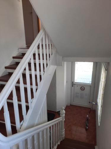 a hallway with a white staircase with a window at Green Hill Apartments - Feldkirch in Feldkirch