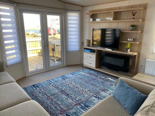 a living room with a couch and a flat screen tv at Beachfront Lodge, Lossiemouth Bay in Lossiemouth