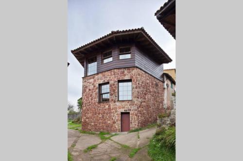una casa de ladrillo y piedra con techo de gambrel en Casita de la plaza Lugás, en Villaviciosa