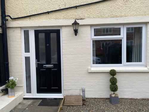 a house with a black door and two windows at 10 Bromleys Court in Church Stretton
