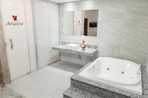 a bathroom with a tub and a sink and a mirror at Pousada Adega Cipo in Serra do Cipo