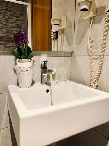 a white bathroom sink with a vase of flowers on it at Hotel Astrid in Milan