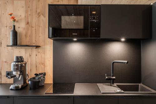 a kitchen with a sink and a microwave above a counter at s'Hoamatl Dorfkrug Appartements in Seefeld in Tirol