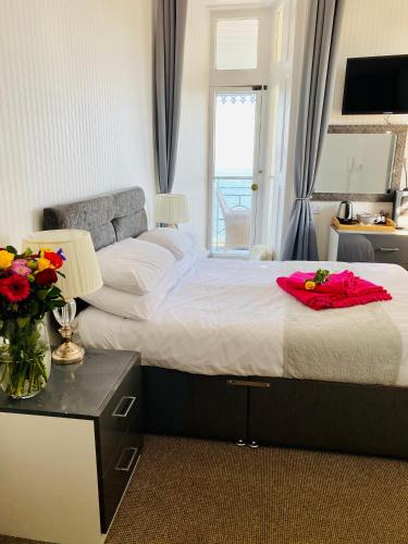a bedroom with a bed with a vase of flowers on it at Villa Mentone Hotel in Shanklin