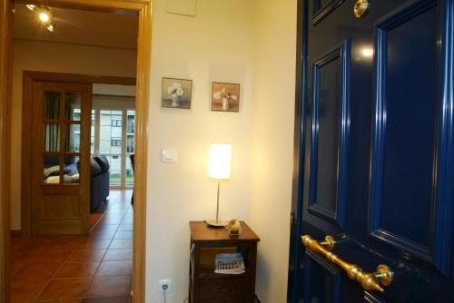 a hallway with a blue door and a lamp on a table at URDINETXE in Luyando