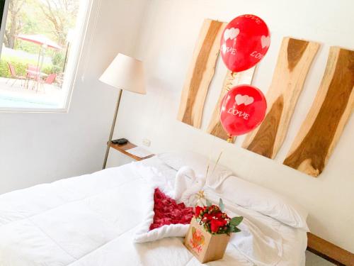 a room with a bed with balloons and a gift at VILLA NAPOLI in Santa Ana