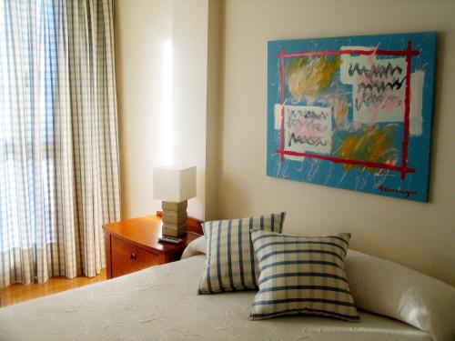 1 dormitorio con 1 cama y una pintura en la pared en URDINETXE, en Luyando