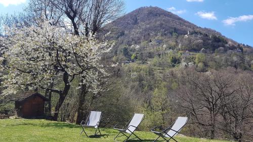 three chairs sitting in a field in front of a mountain at Baita Eleonora in Argegno