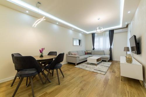 sala de estar con mesa, sillas y sofá en Apartments Centrale 28, en Podgorica