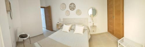 um quarto com uma cama com almofadas brancas e espelhos em RELAX CHICLANA-Aparcamiento privado-TV Cable-WifiPlus-Aire Acond-Incluido em Chiclana de la Frontera