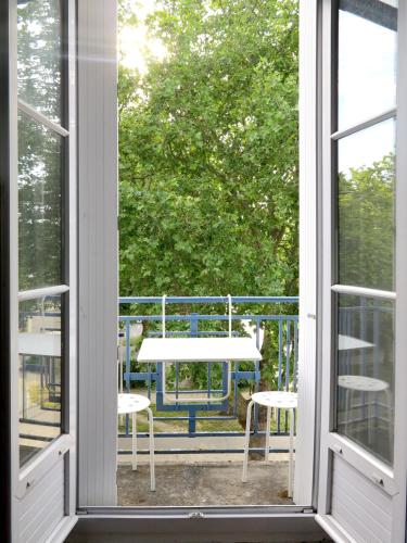 une fenêtre ouverte avec une table et des chaises sur un balcon dans l'établissement Appartement vue latérale sur océan, à Saint-Nazaire
