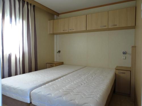 a bedroom with a white bed and a window at Chalet 3 in Meliskerke