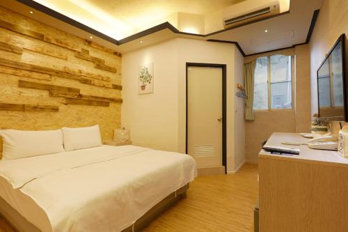 een slaapkamer met een wit bed en een bureau bij At Tainan Inn in Tainan