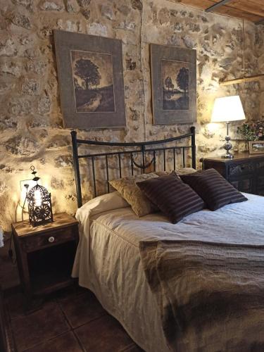 Un dormitorio con una cama y una pared de piedra. en LA HUETA Bajo, en Orcera