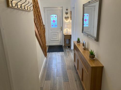 a hallway with a staircase and a mirror and a door at Hopefield Premium Holiday Home Portrush Sleeps 10 4 bedrooms in Portrush