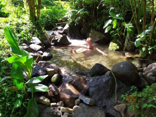 a person in a pool of water in a creek at Mindo Eco Chalet con Rio y Cascada in Mindo