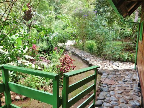 a garden with a green fence and a stone path at Mindo Eco Chalet con Rio y Cascada in Mindo