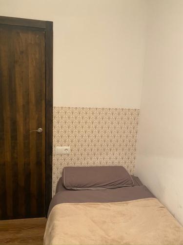 a small bedroom with a bed and a wooden door at Apartamento Casa Latre in Barbastro