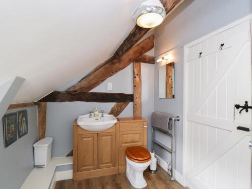 a bathroom with a wooden toilet and a sink at The Old Barn in Hereford