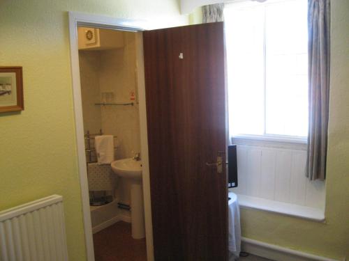 ein Bad mit einem Waschbecken, einem WC und einem Fenster in der Unterkunft The Red Lion Hotel in Bredwardine