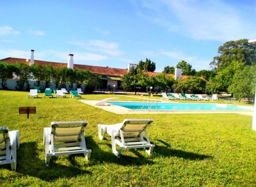 a group of chairs sitting in the grass by a pool at Casas Herdade do Convento da Serra in Almeirim
