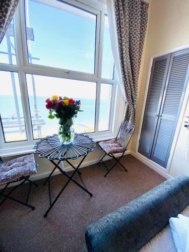 a living room with a table with a vase of flowers at Villa Mentone Hotel in Shanklin