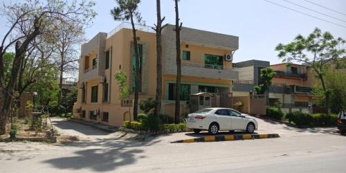 a white car parked in front of a building at Butt Lodges 2 in Islamabad