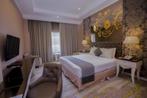 a hotel room with a bed and a chair and a television at Sutanraja Hotel & Convention Centre in Soreang