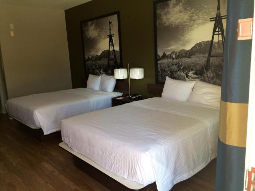 two beds in a hotel room with white sheets at Super 8 by Wyndham San Antonio Near Fort Sam Houston in San Antonio