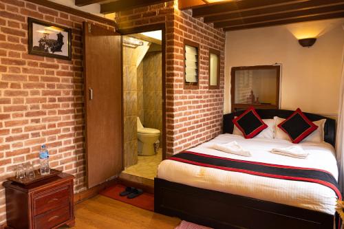 a bedroom with a bed and a brick wall at Tulaja Boutique Hotel in Bhaktapur