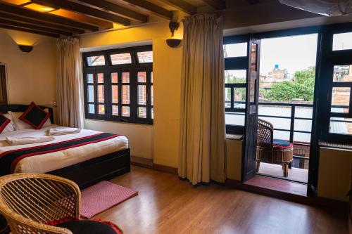 a bedroom with a bed and a balcony withwindows at Tulaja Boutique Hotel in Bhaktapur