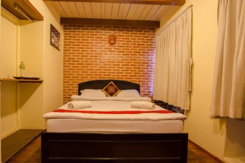 a bed in a room with a brick wall at Tulaja Boutique Hotel in Bhaktapur