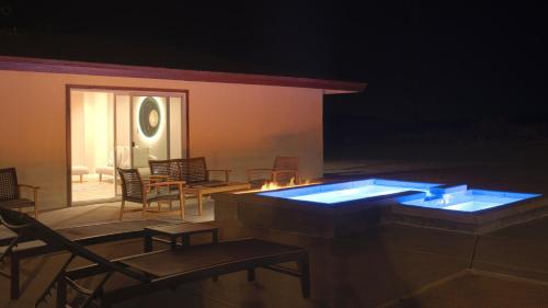 a room with chairs and a swimming pool at night at @ Marbella Lane - The Moon Designer Home right behind the JTNP in Joshua Tree