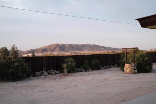 a yard with a fence and a mountain in the background at @ Marbella Lane - The Moon Designer Home right behind the JTNP in Joshua Tree
