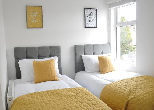 1 dormitorio con 2 camas con almohadas amarillas en The Social - Cardiff's Best For Larger Groups, en Cardiff
