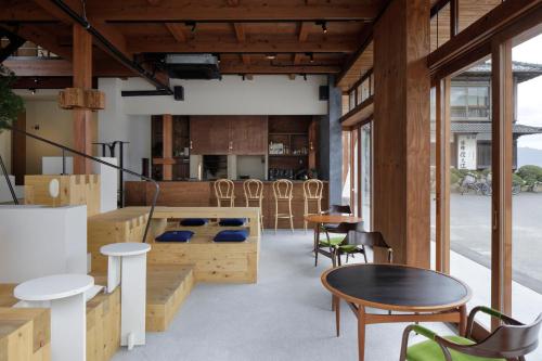 Habitación con muebles de madera, mesas y sillas. en SOIL Setoda, en Onomichi