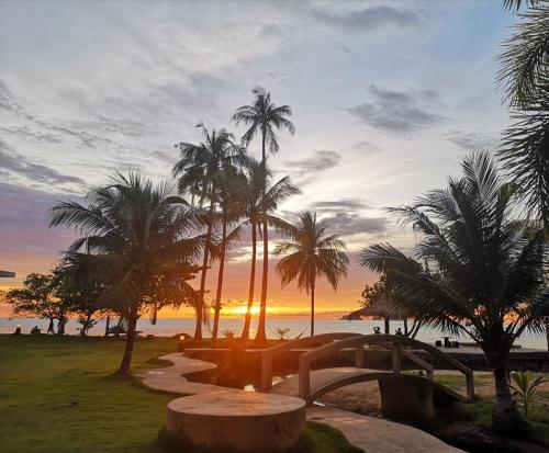 a sunset at the beach with palm trees and a pathway at Koh Chang Bailan Beach Resort in Ko Chang