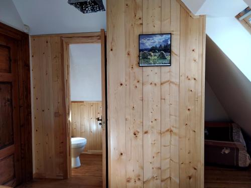 a bathroom with a toilet and a wooden wall at Gungas in Ādaži
