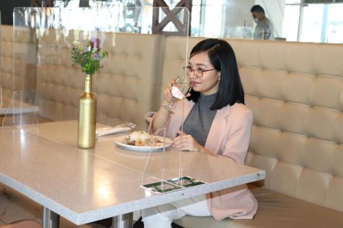 a woman sitting at a table drinking a glass of wine at Hotel101 - Manila in Manila