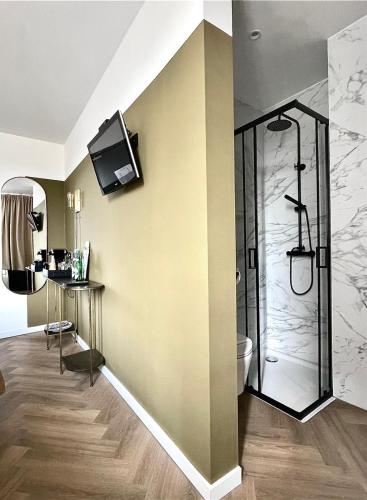 a bathroom with a shower and a television on the wall at Valkenhof in Valkenburg