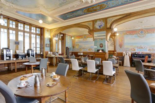 Hôtel Arc en Ciel et SPA - Les Sables d'Olonne في لي سابلِ دولونْ: غرفة طعام بها طاولات وكراسي ومكتبة